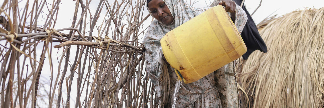 Een Keniaanse vrouw giet water over in een tank.