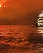 Superyacht against backdrop of fire