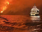 Superyacht against backdrop of fire